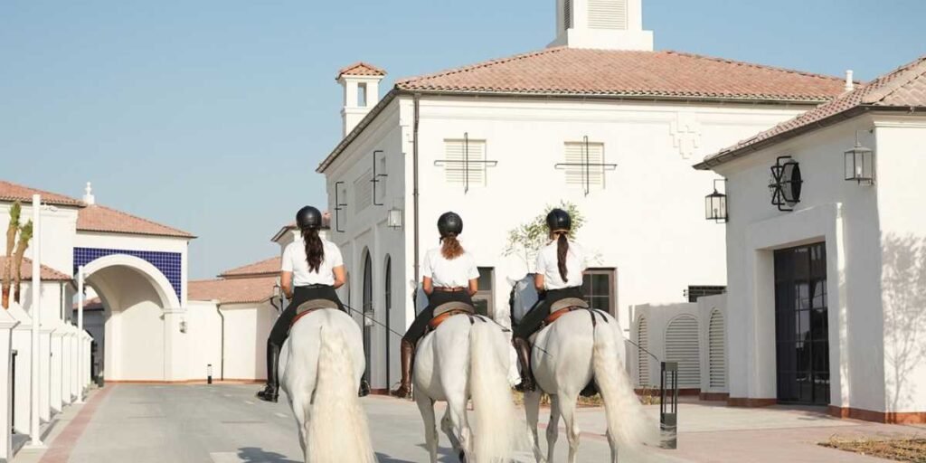 Three riders on white horses riding toward ADREA courtyard at Jubail Island