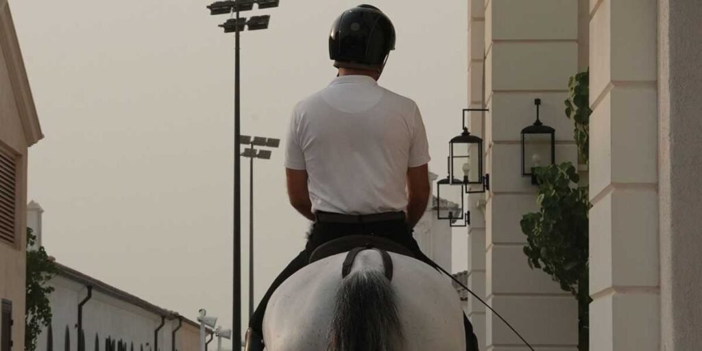 Rider on a white horse on a stable walkway at ADREA, Jubail Island