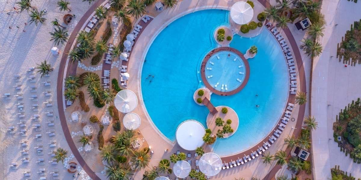 Aerial view of pool, beach, and palm-lined leisure area at Erth Abu Dhabi resort